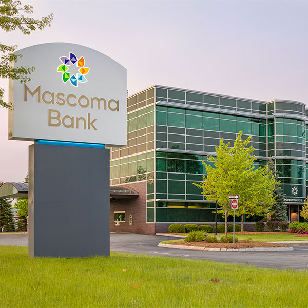 White River Junction Main Office - Glass building with grass, trees and large Mascoma Bank sign in the foreground