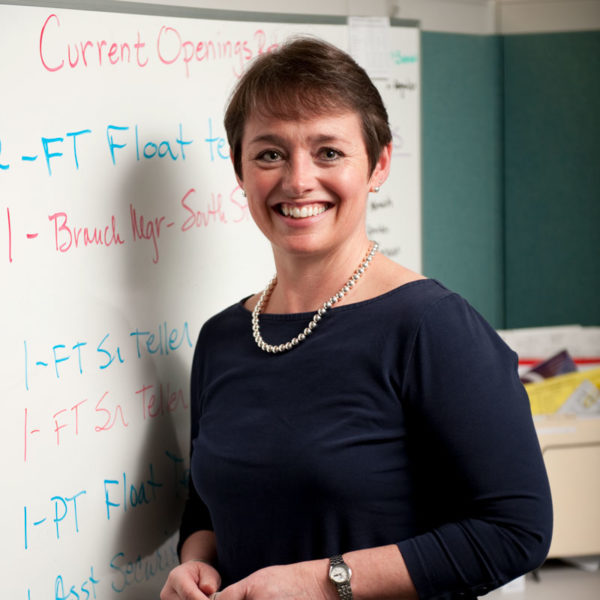 adult women standing in front of a white board smiling at the camera