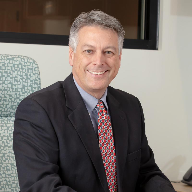 Peter Jones sitting behind a desk with a large, welcoming smile