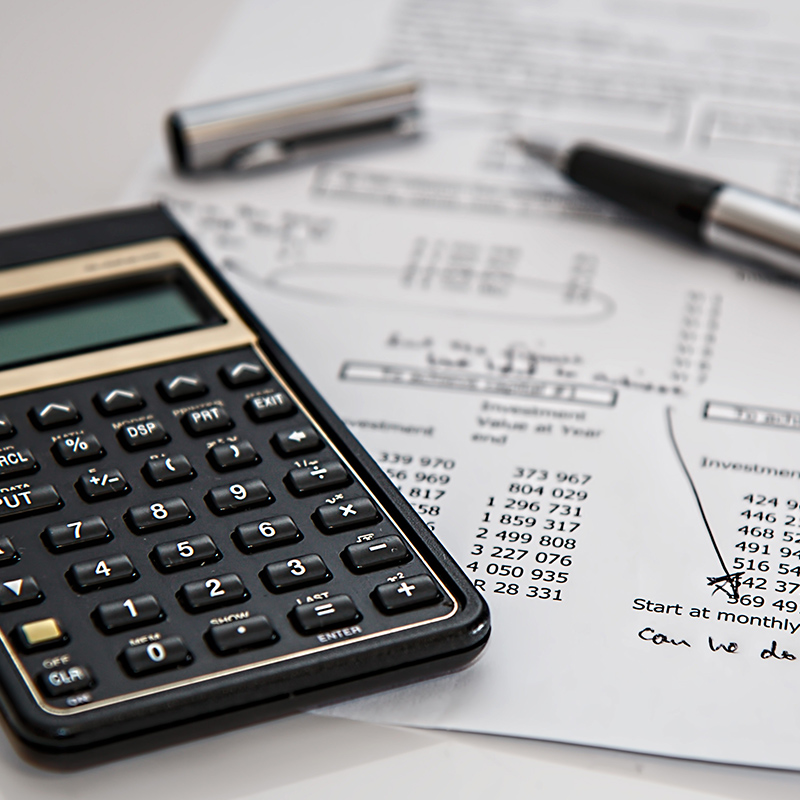 Black calculator next to a silver and black pen resting on a white paper with financial numbers showing