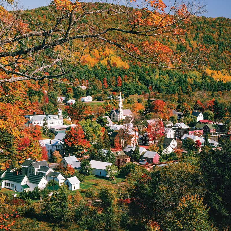 Country town at base of tree covered mountain with autumn colors