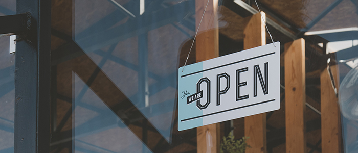 we are open sign hanging on the entrance door of a small cafe. 