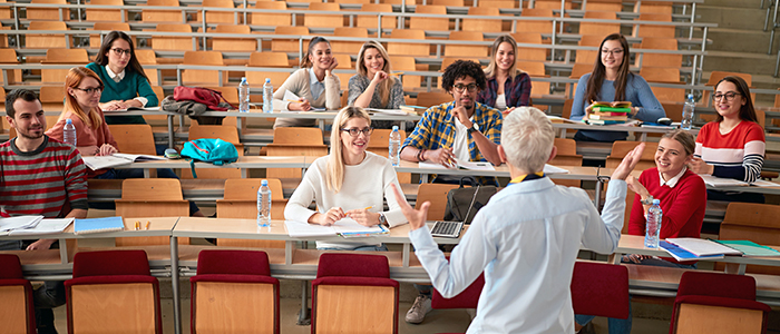 A professor lectures to a group of multi-racially diverse students in a university lecture hall